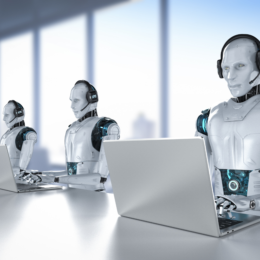Três robôs estão sentados em uma mesa usando laptops.