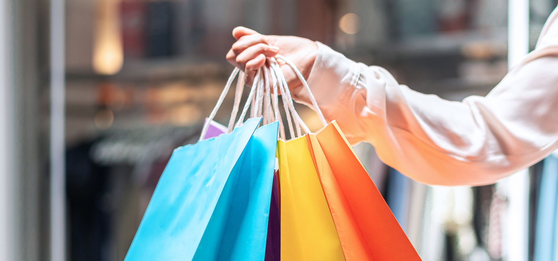Uma mulher está segurando um monte de sacolas de compras coloridas.