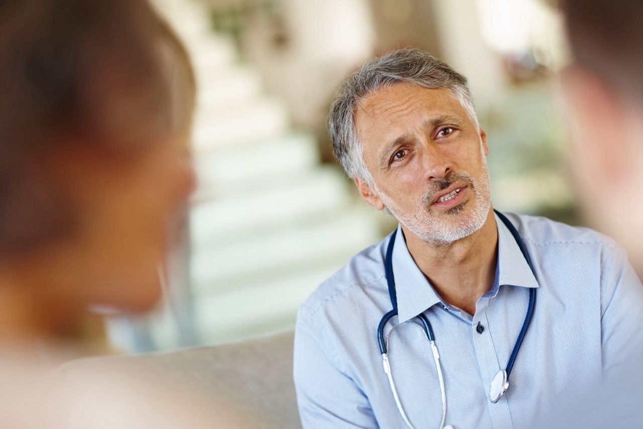 A doctor with a stethoscope around his neck is talking to a patient.