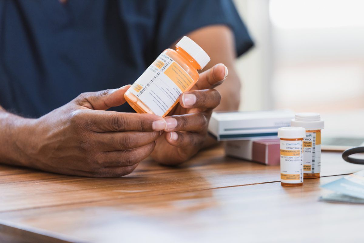 A man is holding a bottle of pills in his hands.