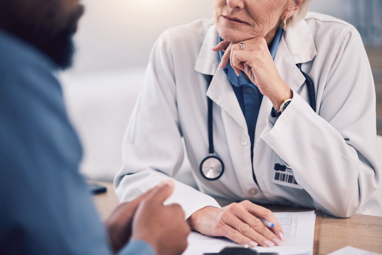 A doctor is sitting at a desk talking to a patient.