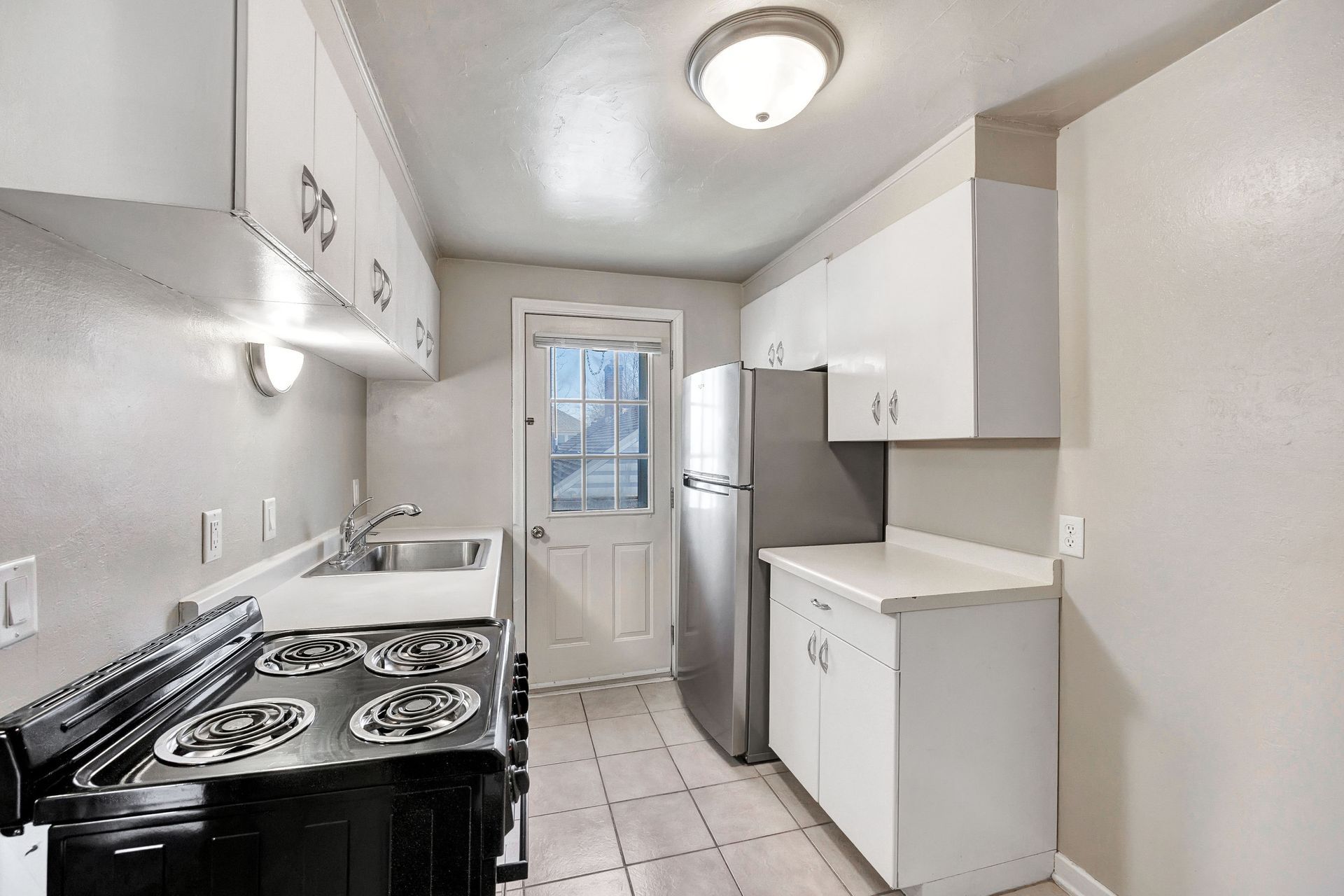 A kitchen with a stove , refrigerator , sink and cabinets.