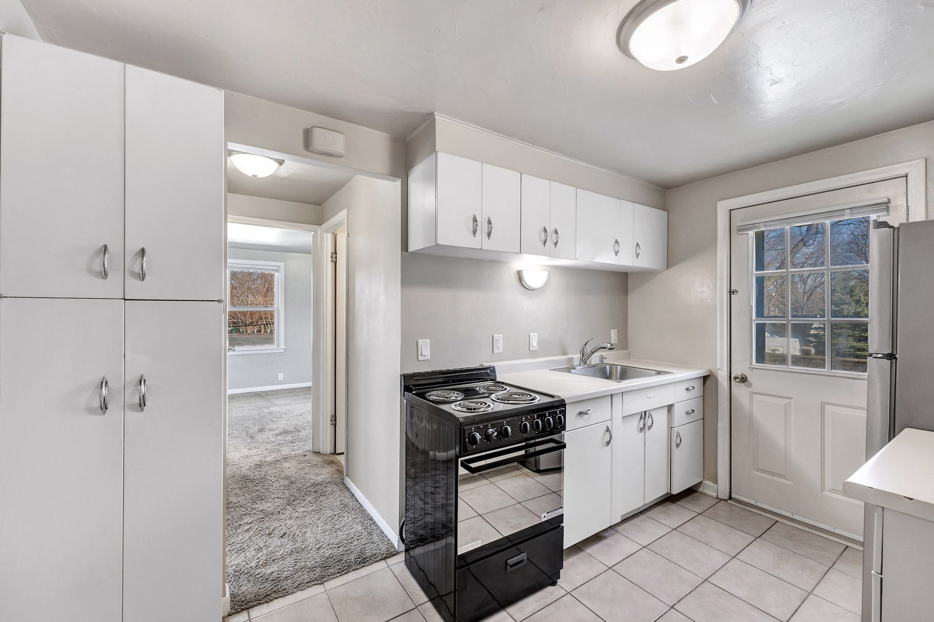 A kitchen with white cabinets , a stove and a refrigerator.