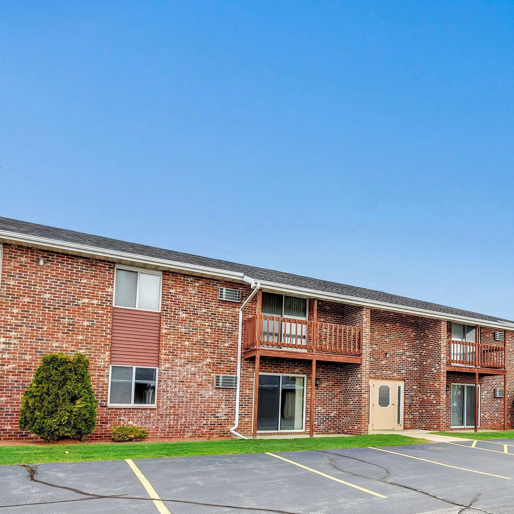 A brick apartment building with a parking lot in front of it.