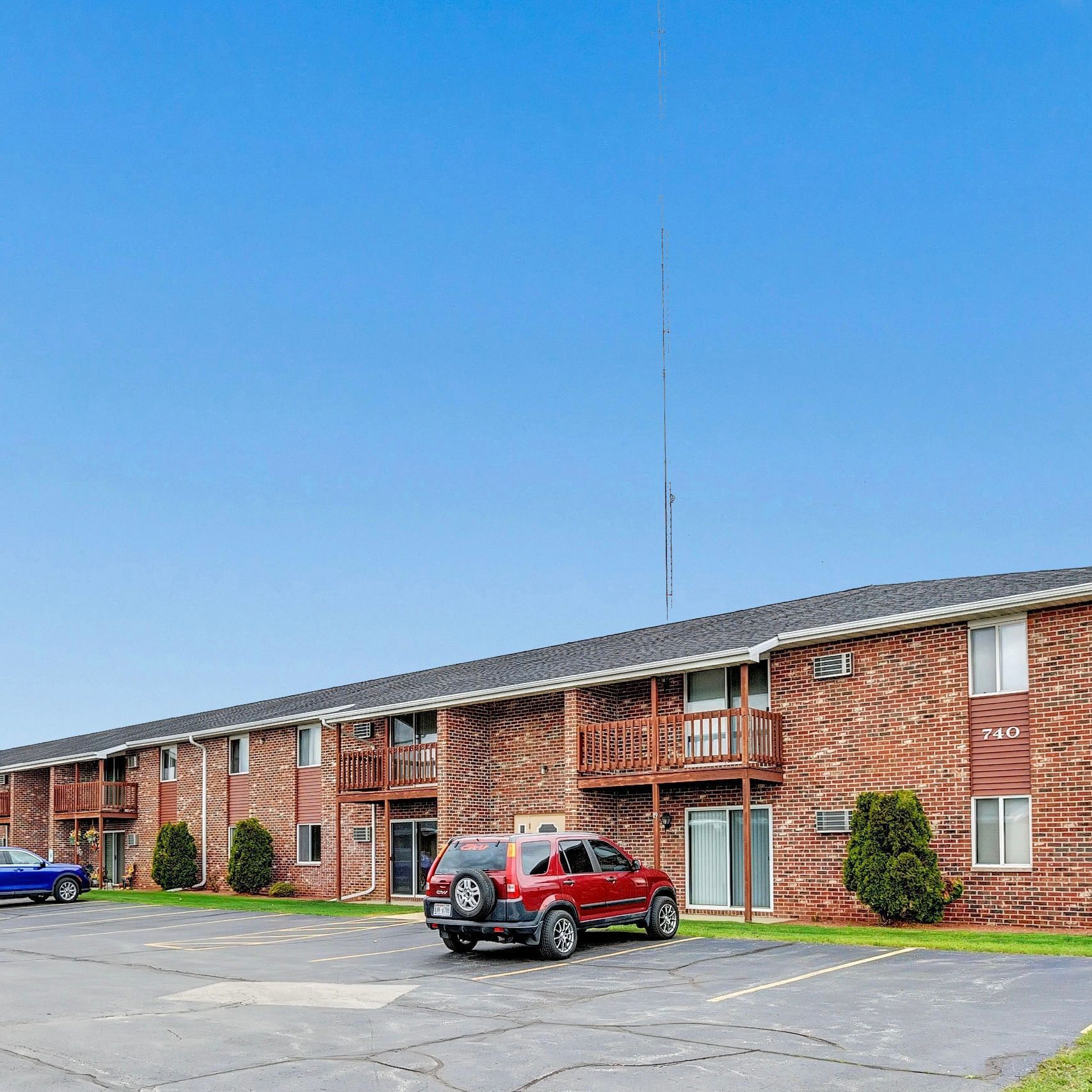 A red suv is parked in front of a brick apartment building.