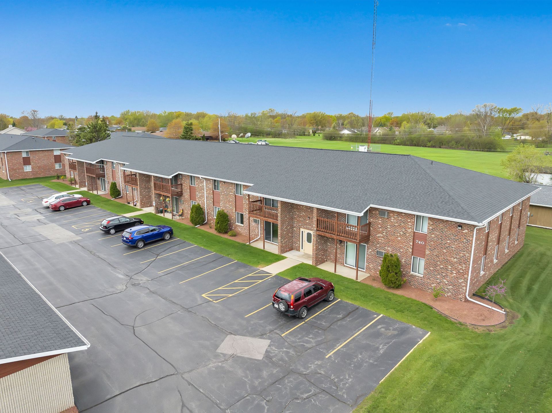 An aerial view of a brick apartment building with cars parked in front of it.