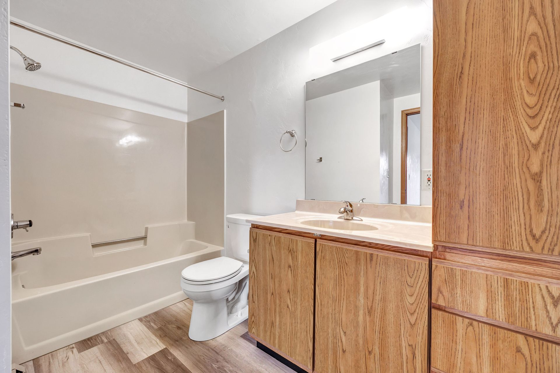 A bathroom with a toilet , sink , bathtub and mirror.