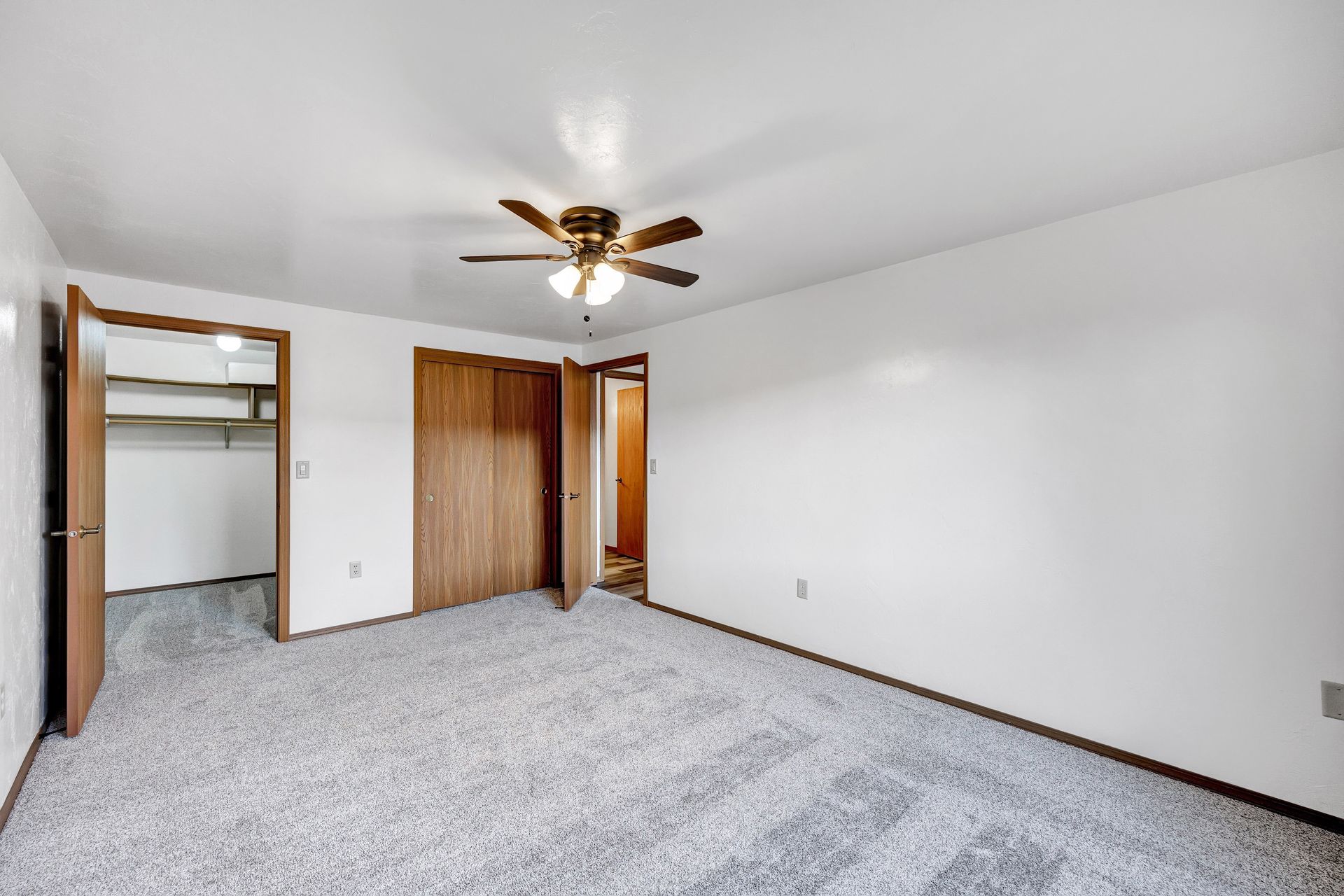 An empty bedroom with a ceiling fan and a walk in closet.