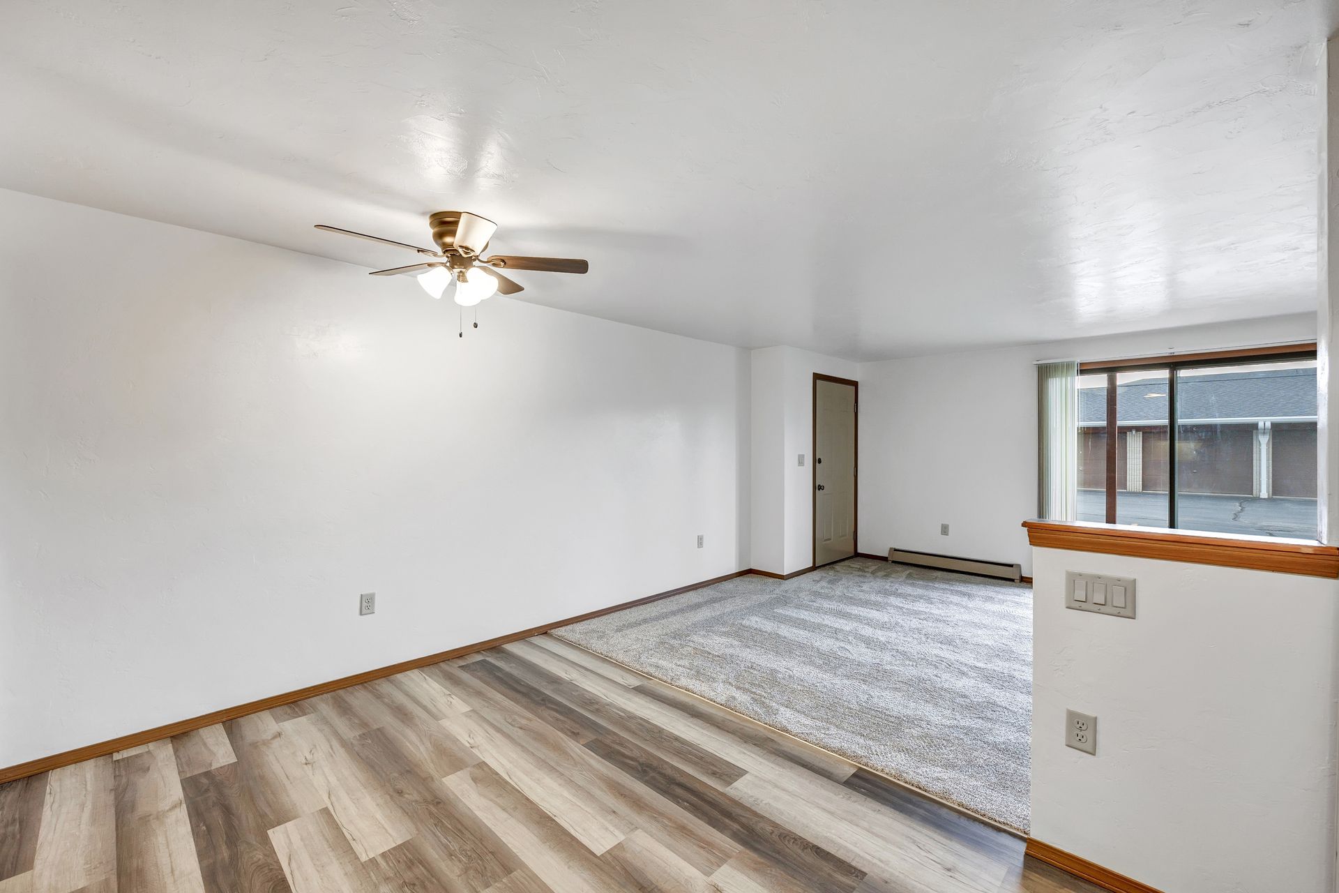 An empty living room with hardwood floors and a ceiling fan.