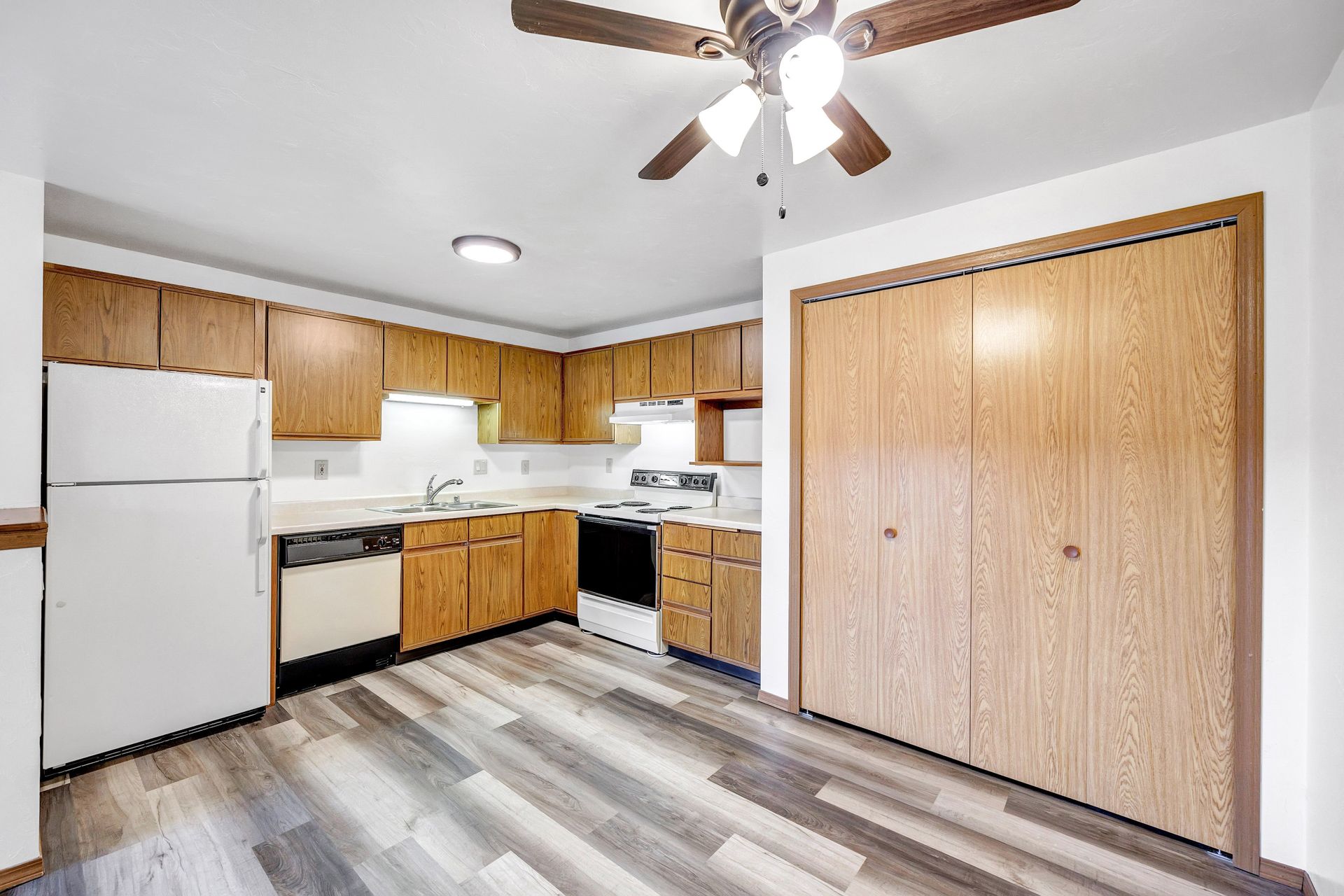 A kitchen with wooden cabinets and a ceiling fan.