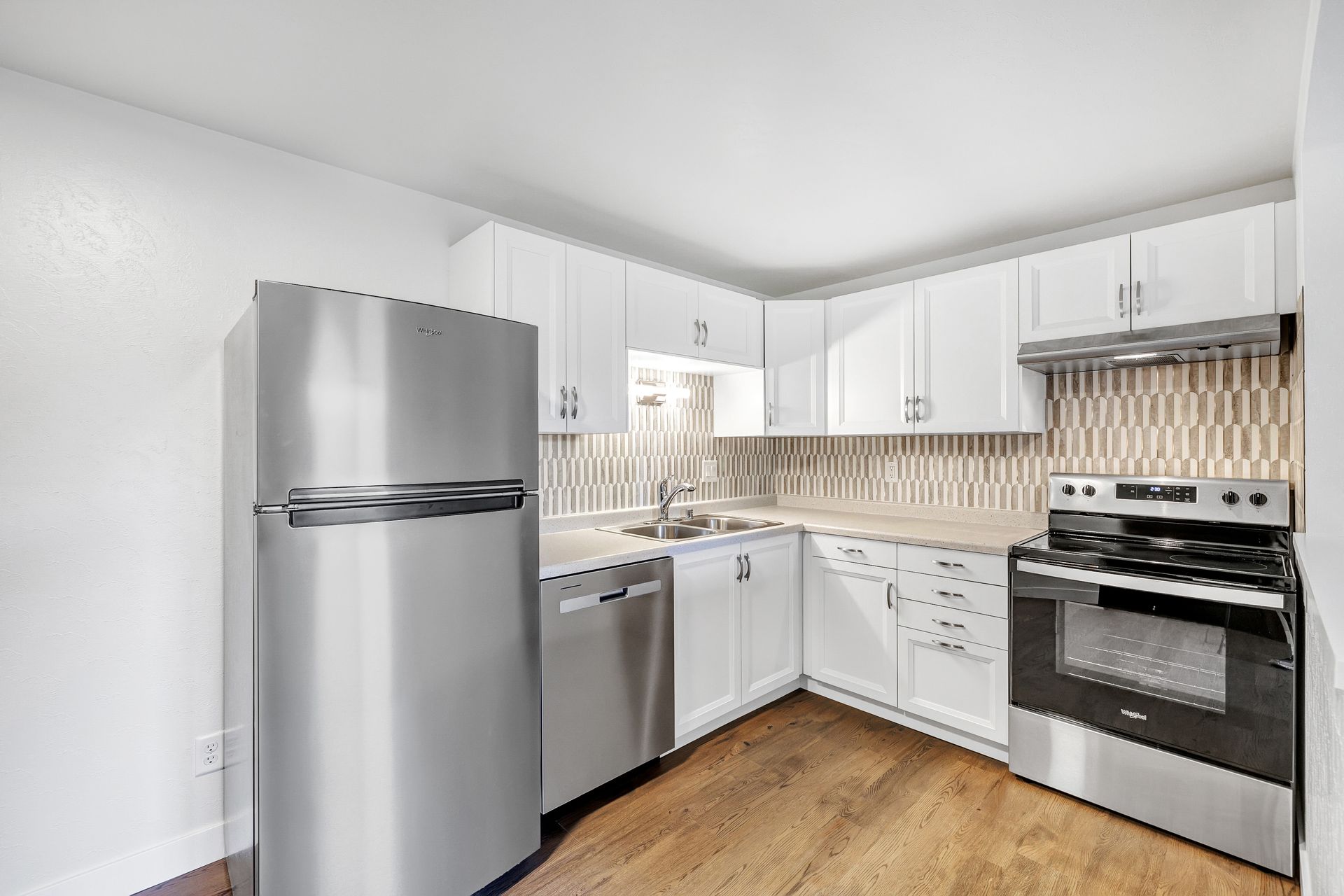 A kitchen with stainless steel appliances and white cabinets.