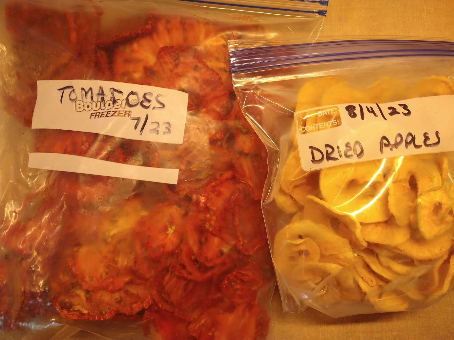 Photo of two freezer bags, one with dried tomato slices and the other with dried apple slices
