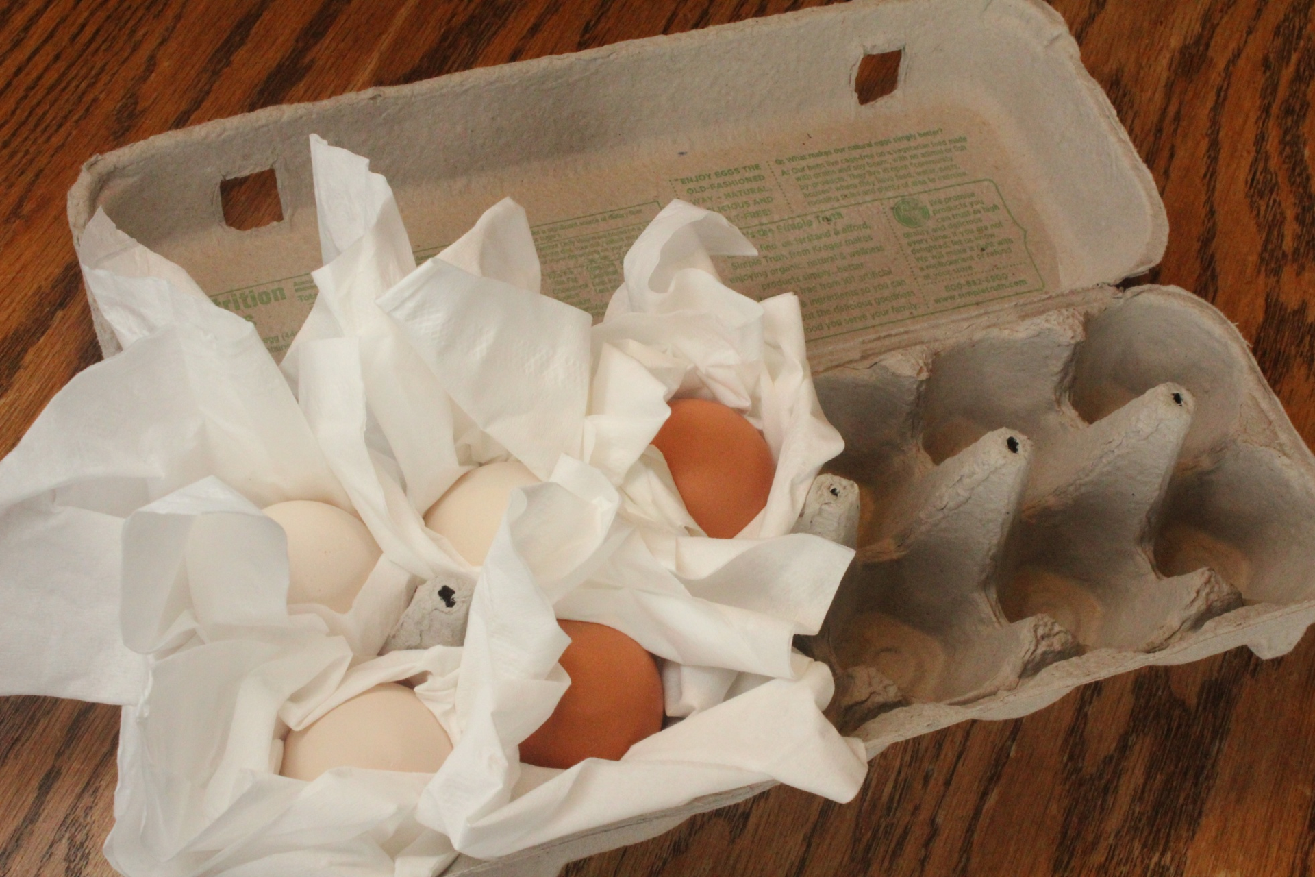 Eggs being wrapped in tissue paper in an egg carton in preparation for shipping