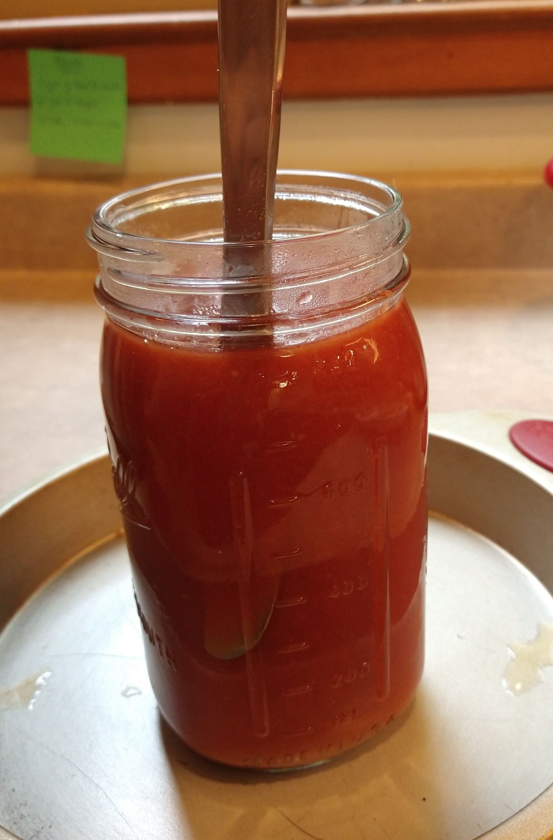 Photo of a knife being placed in full canning jar before putting in canner. Knife will help all air bubbles escape so the jar will seal.