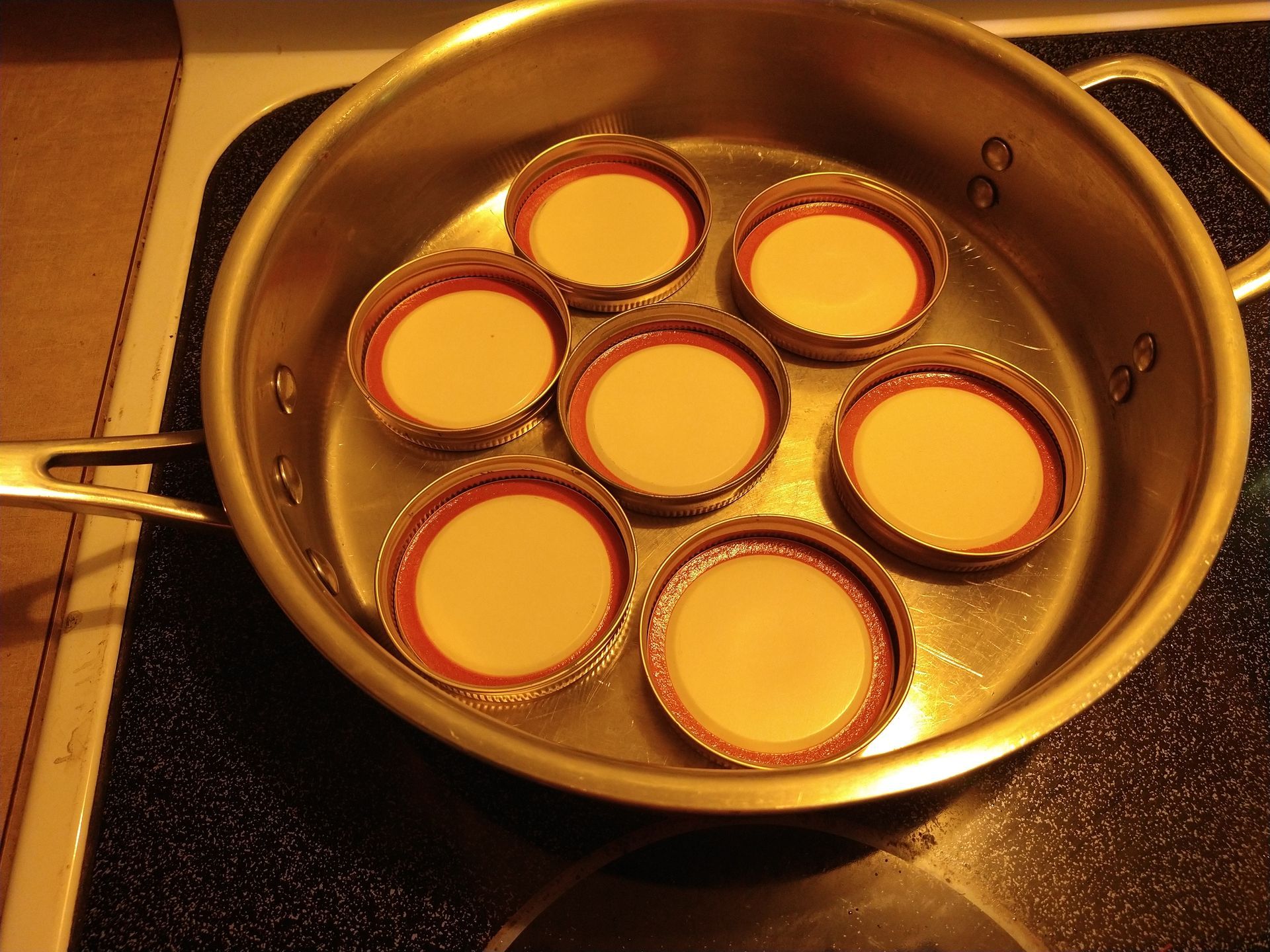 Photo of canning lids and rings in pan on stove