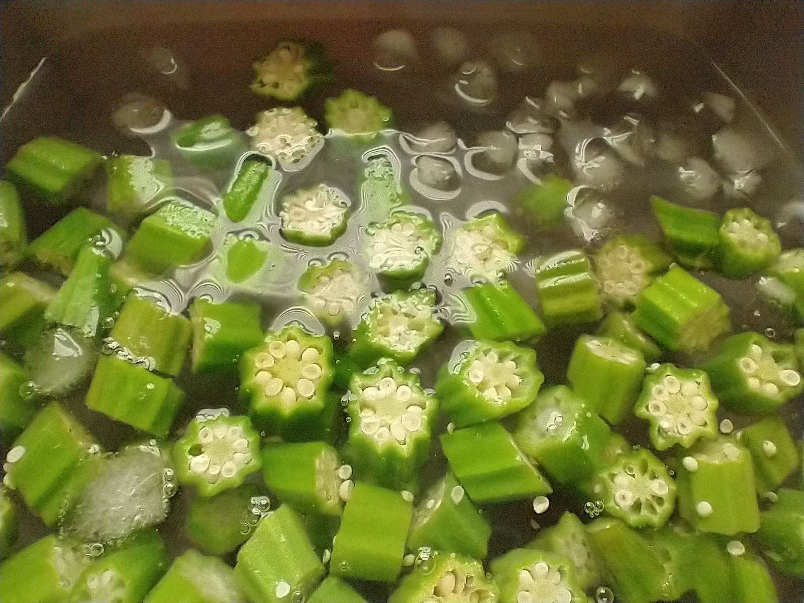 Cut pieces of okra, blanched and cooling in ice water before drying and freezing.