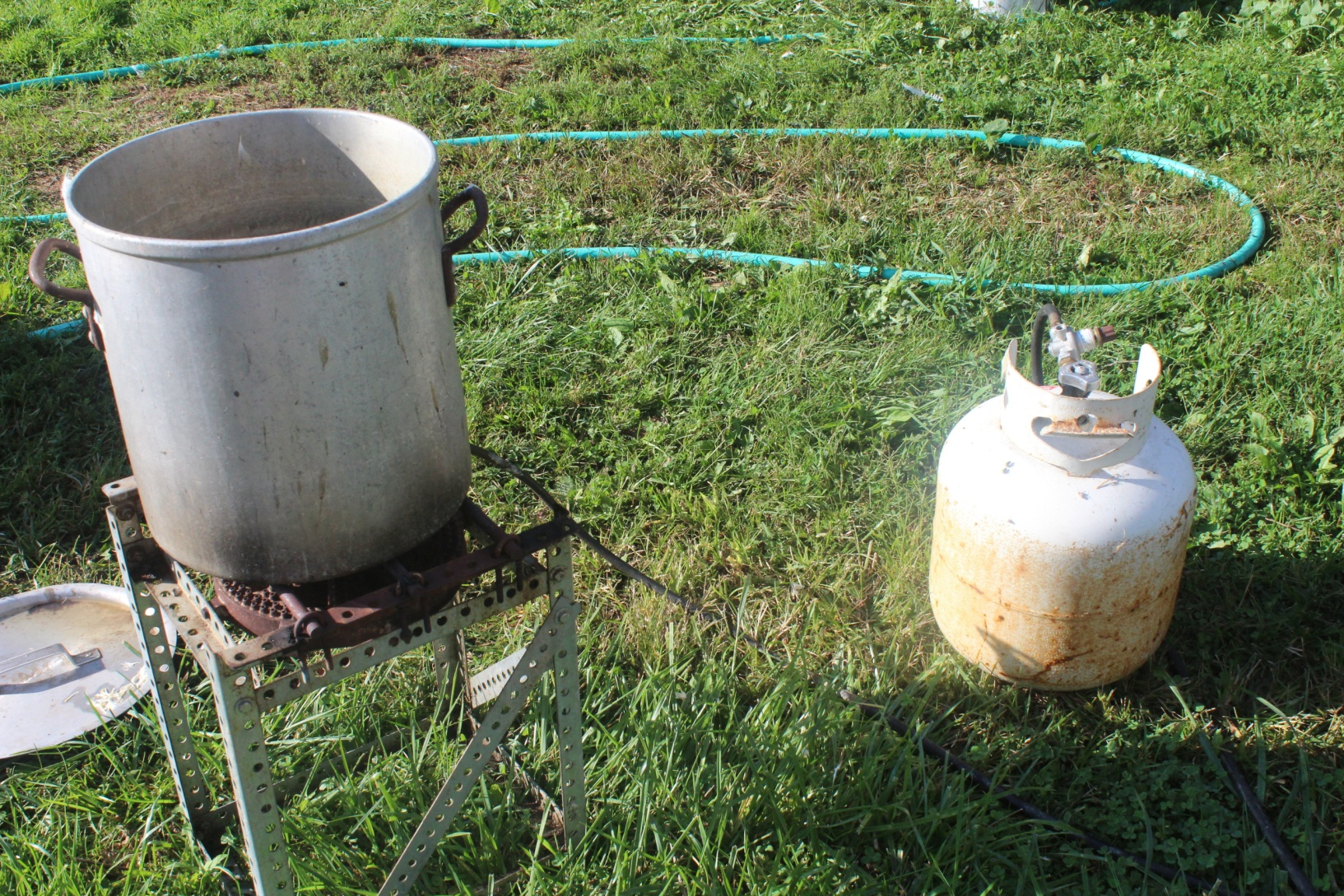 Photo of a large aluminum pot on an outdoor burner adjacent to a propane tank