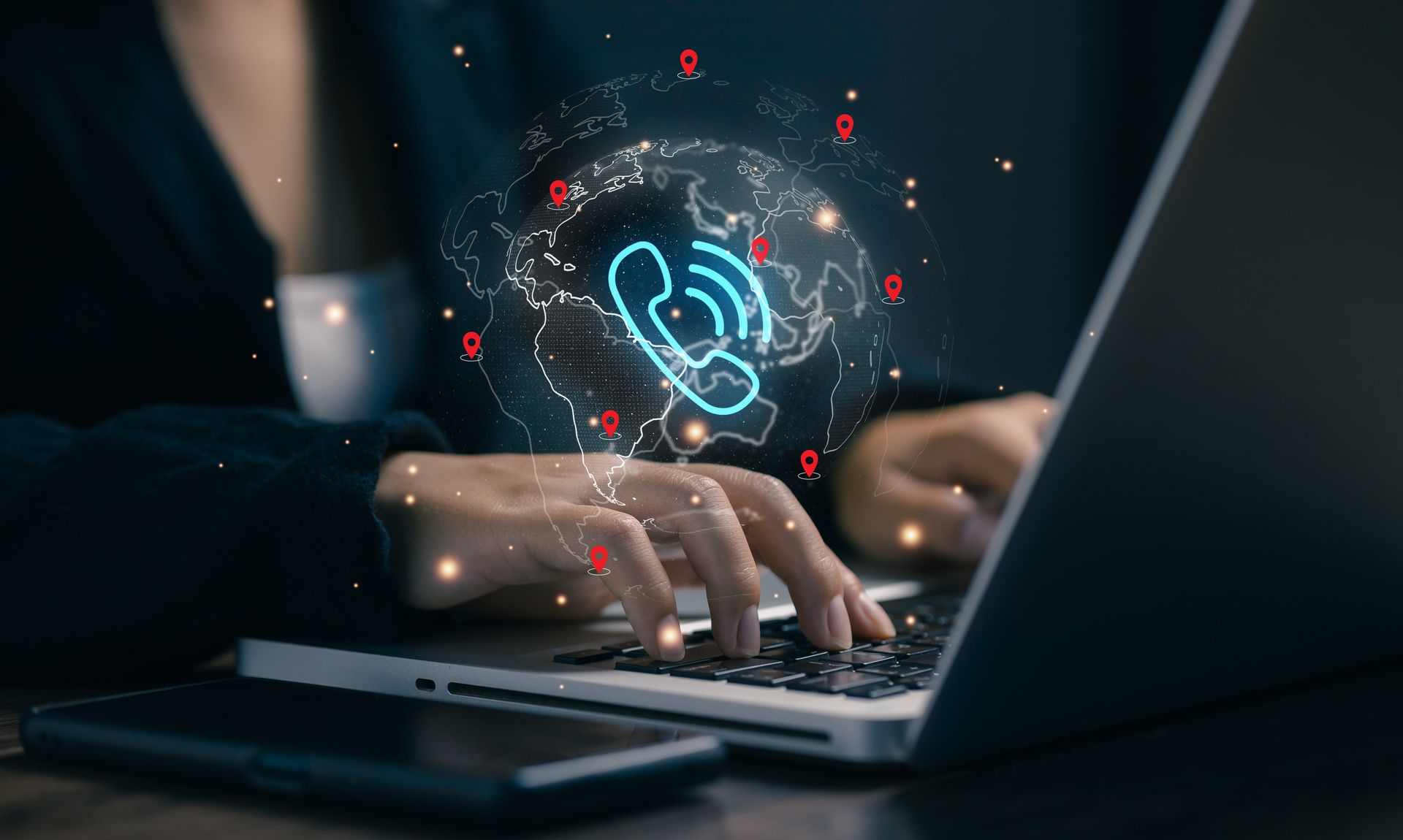 Hands typing on a laptop with a glowing phone icon and digital network symbols above the keyboard