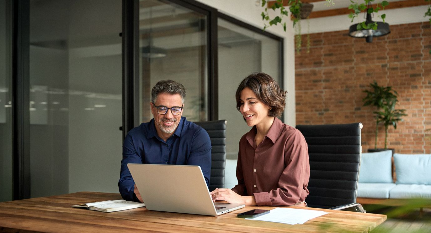 Two people working at a table with a laptop in a modern office