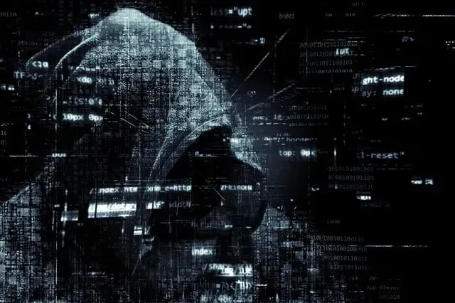 Dark hooded figure in profile overlaid with digital code and network lines in a futuristic cyberpunk scene