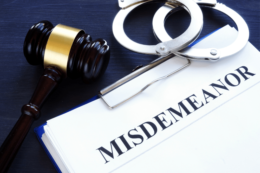 Judge’s gavel beside handcuffs and a file labeled “MISDEMEANOR”