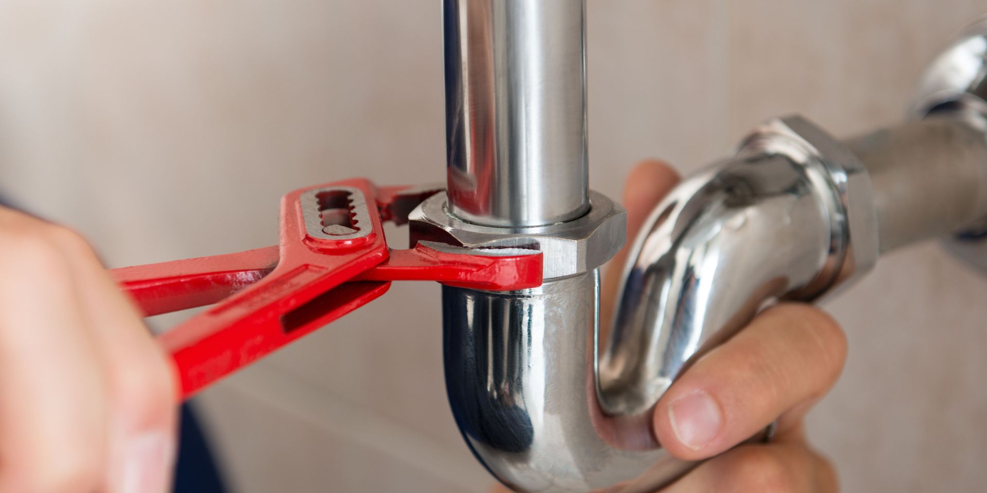 A plumber is fixing a pipe with a wrench.