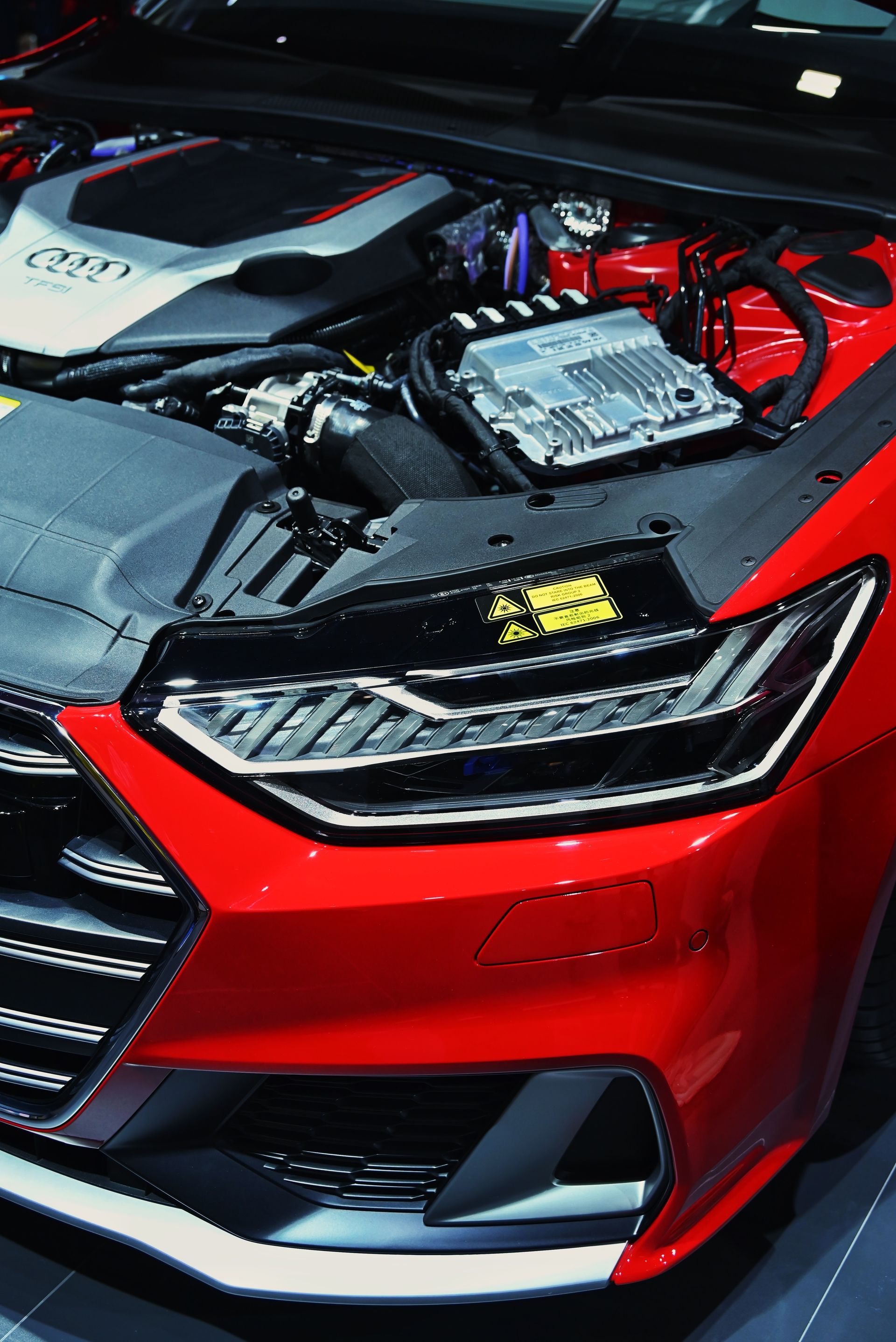 Red sports car with hood open, showing engine details and front headlight