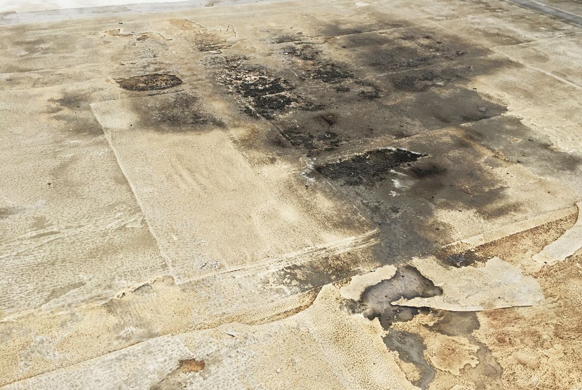 A close up of a concrete floor with a lot of stains on it.
