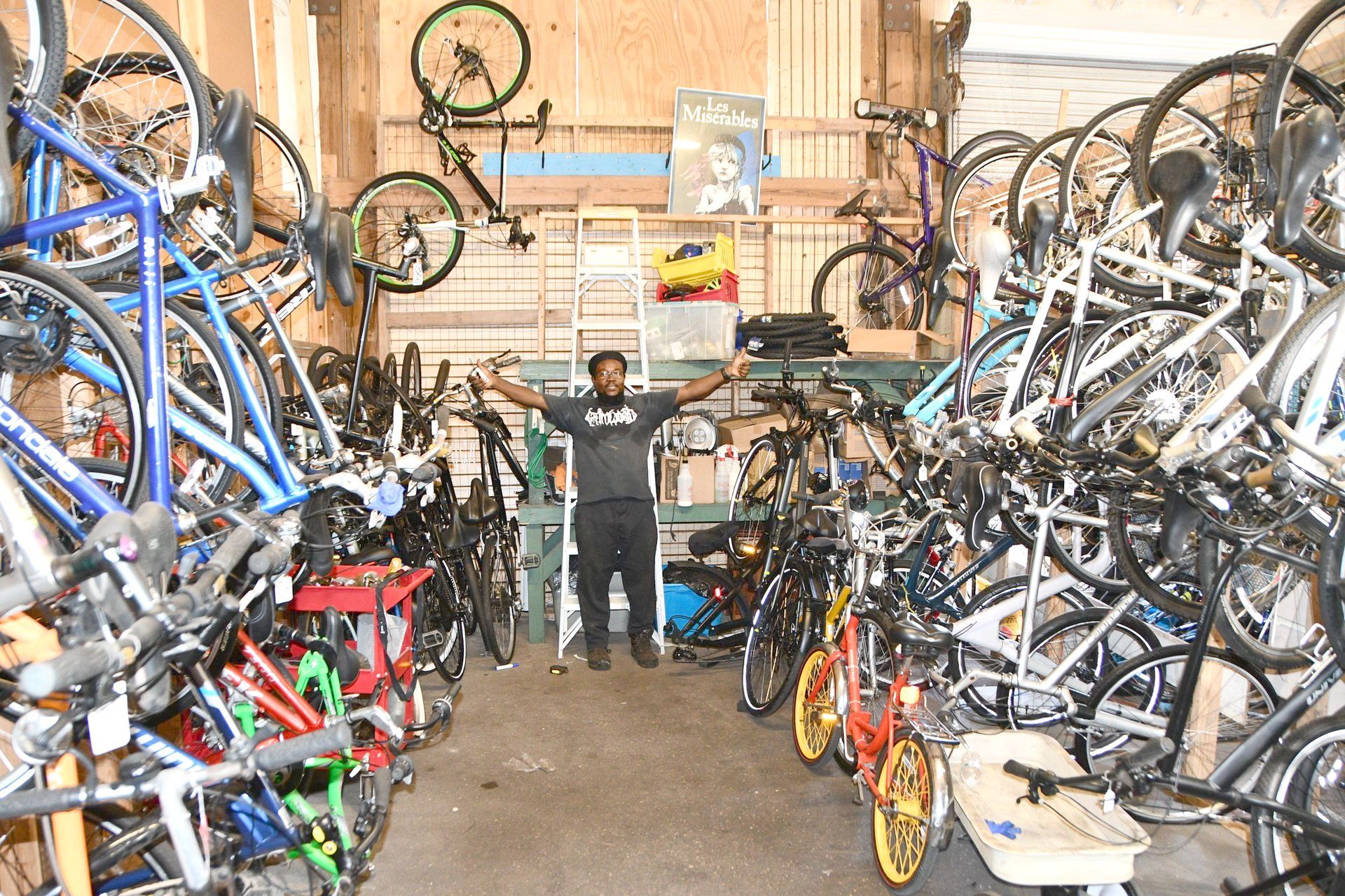 A man is standing in a room filled with lots of bicycles.