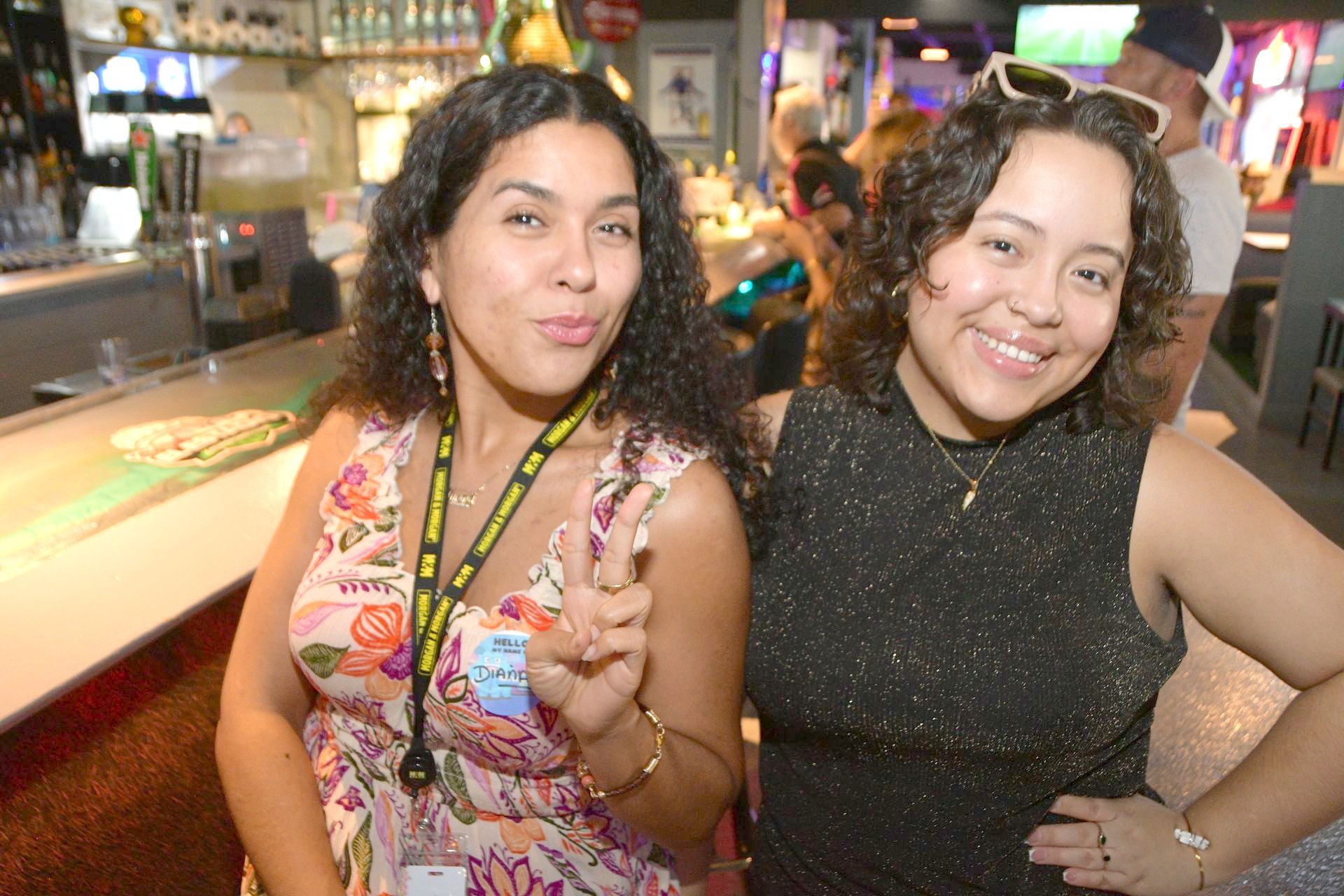 Two women are posing for a picture in a bar.