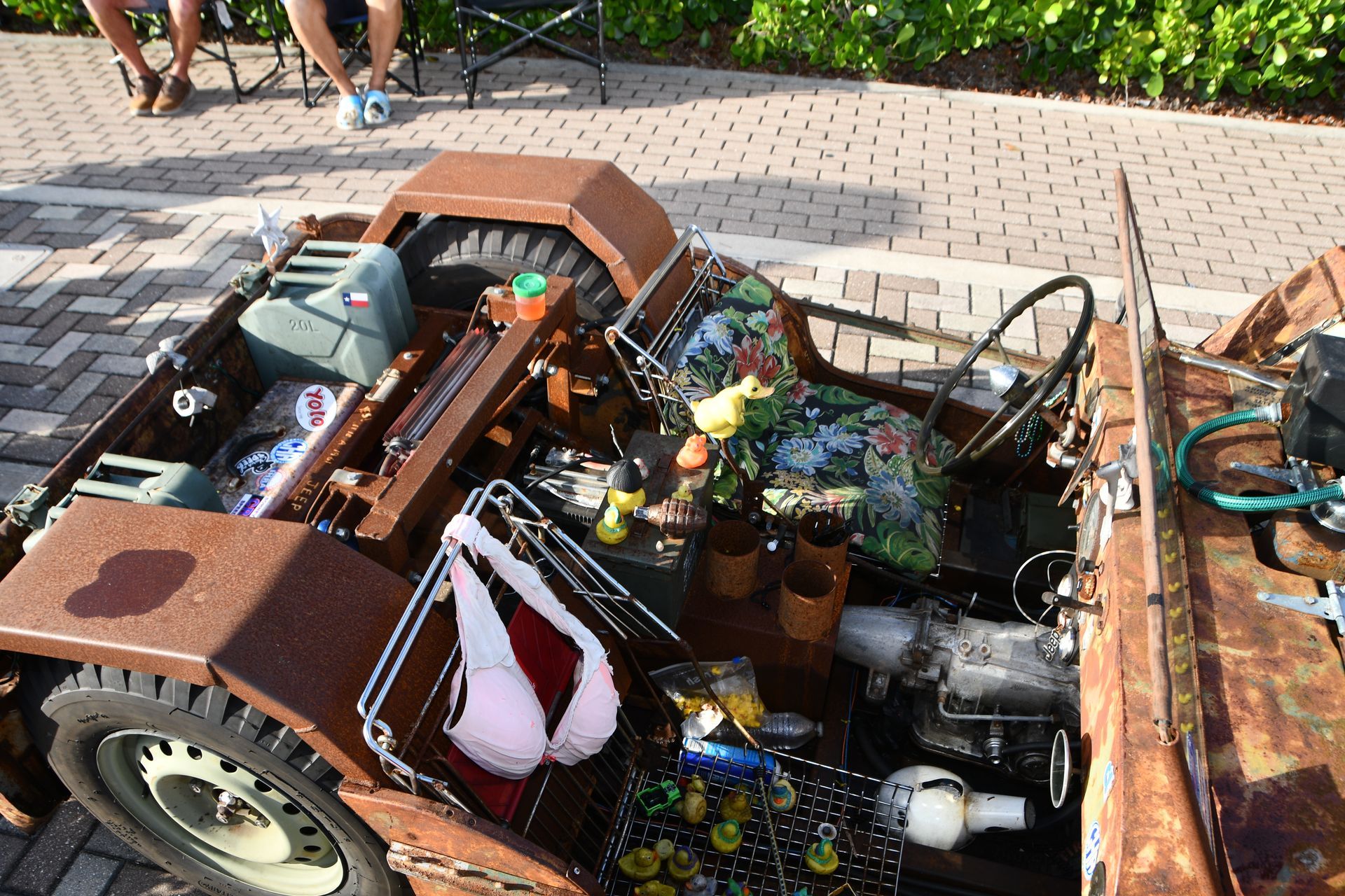 Rusty brown vehicle filled with random items, including a bra and flowers.