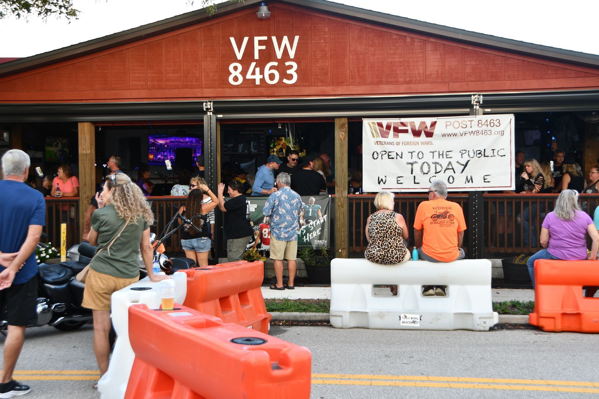 People outside VFW 8463; orange and white barriers in front. Sign: 