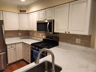 A kitchen with white cabinets , stainless steel appliances and a sink.