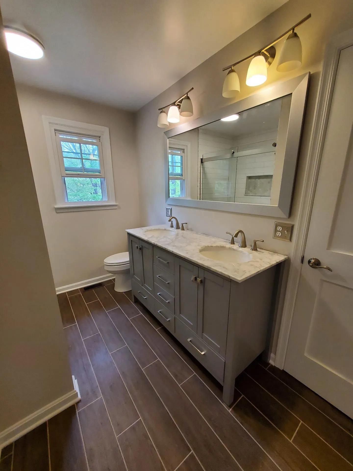 A bathroom with two sinks , a toilet , and a large mirror.
