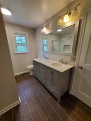 A bathroom with two sinks , a toilet , and a large mirror.