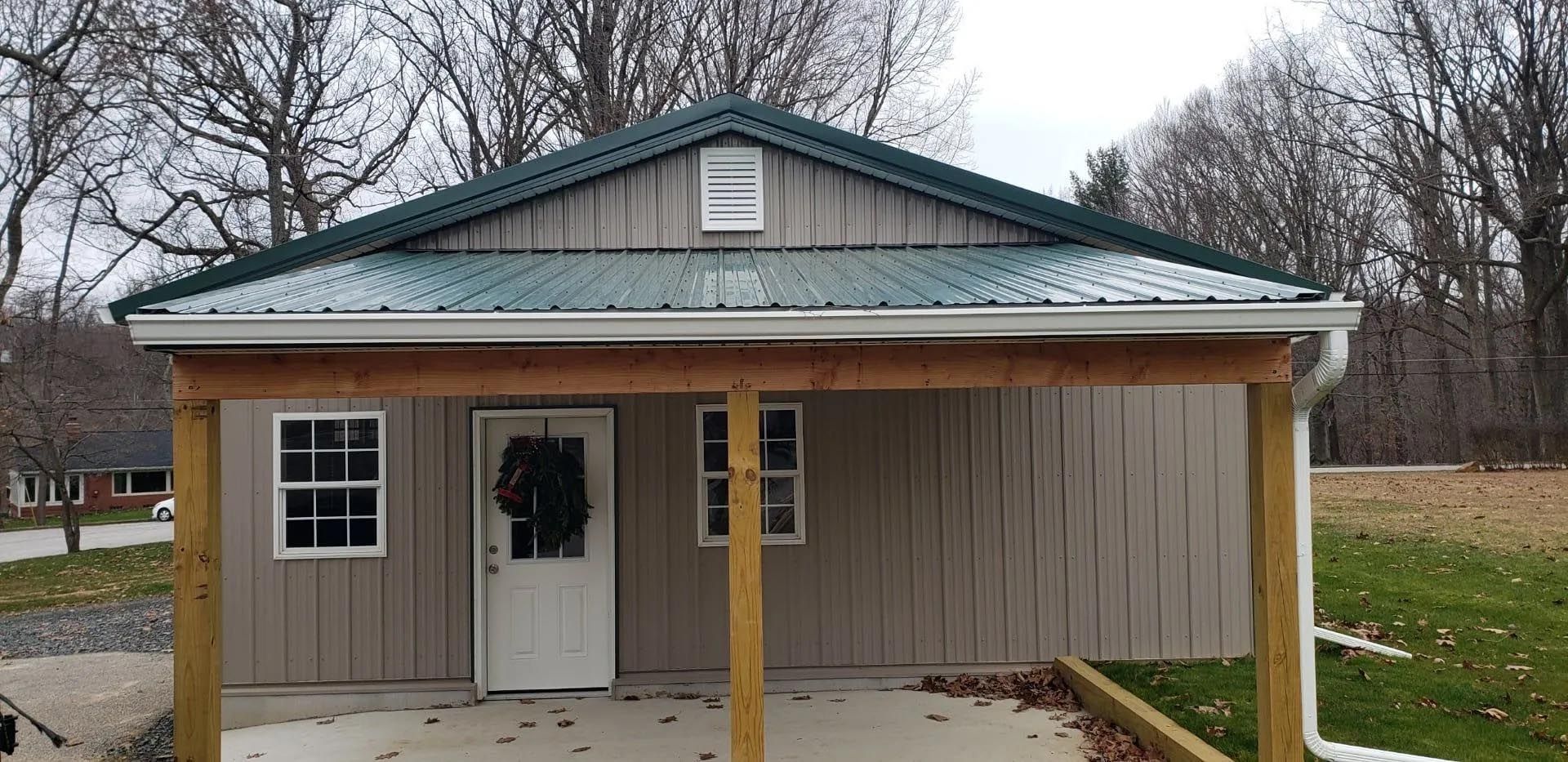 A small house with a green roof and a porch.