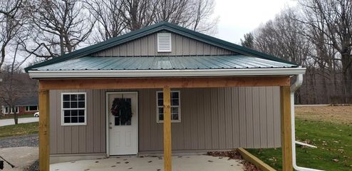 A small house with a green roof and a porch.