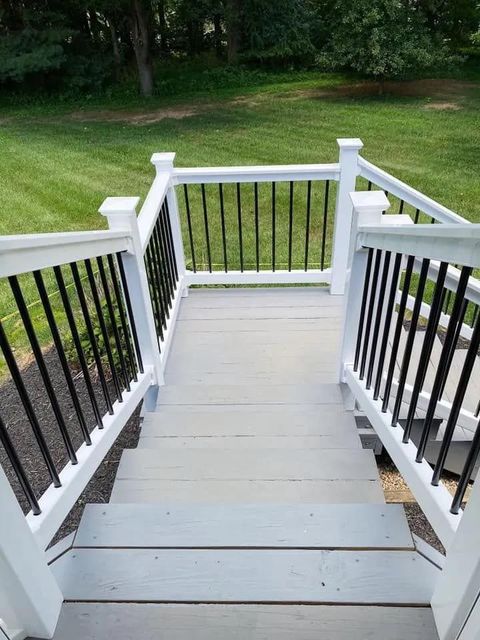 A deck with stairs leading up to it and a black railing.