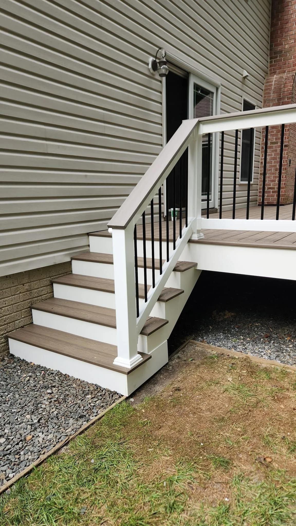 A deck with stairs leading up to it and a white railing.