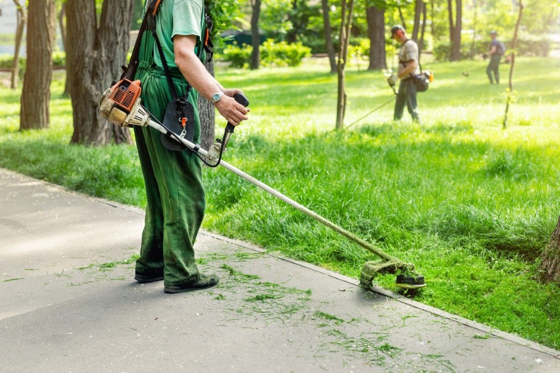 Professional lawn care technician trimming grass at a residential property in Celina, TX.
