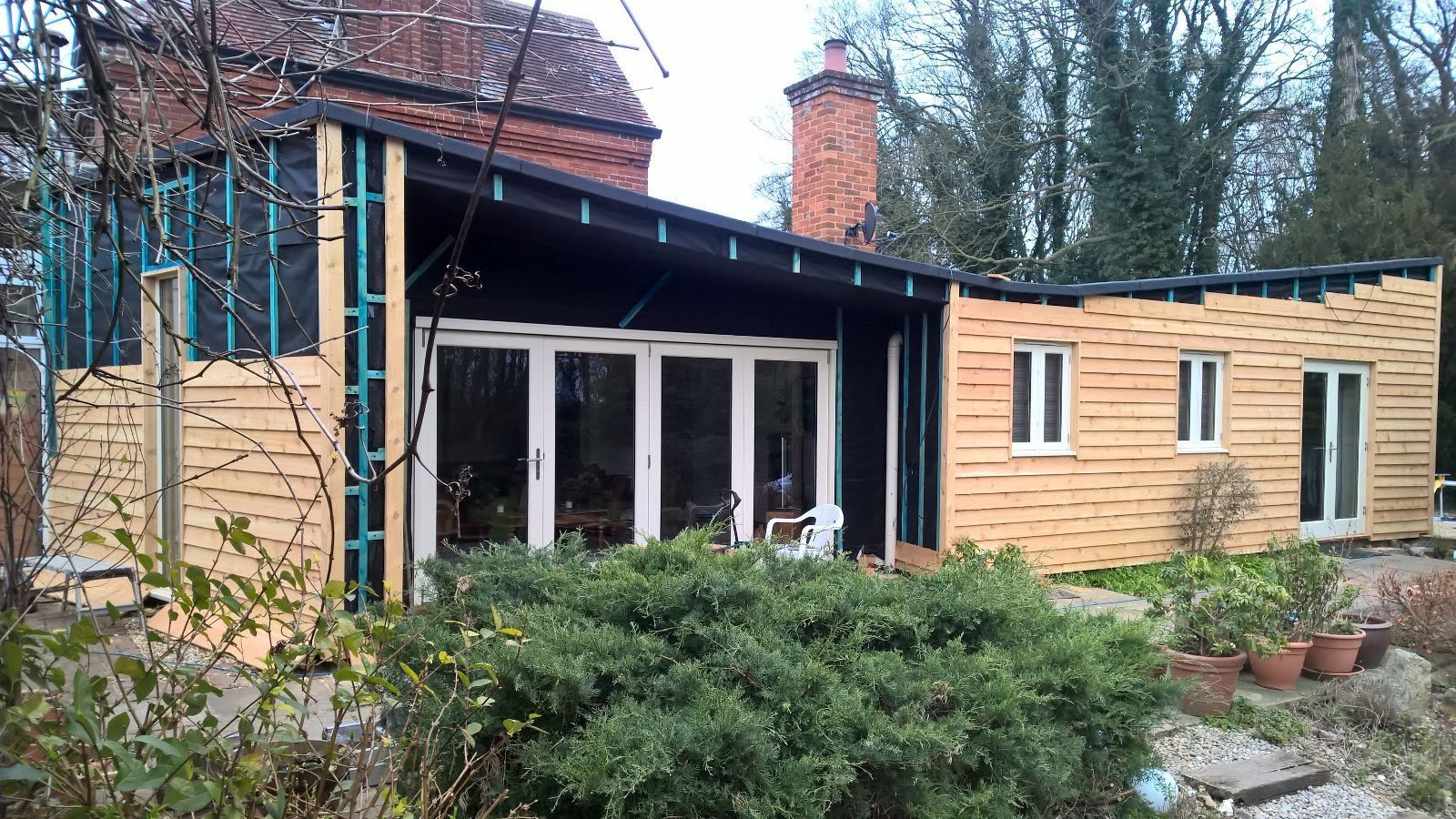 A wooden house with a lot of windows is being built.