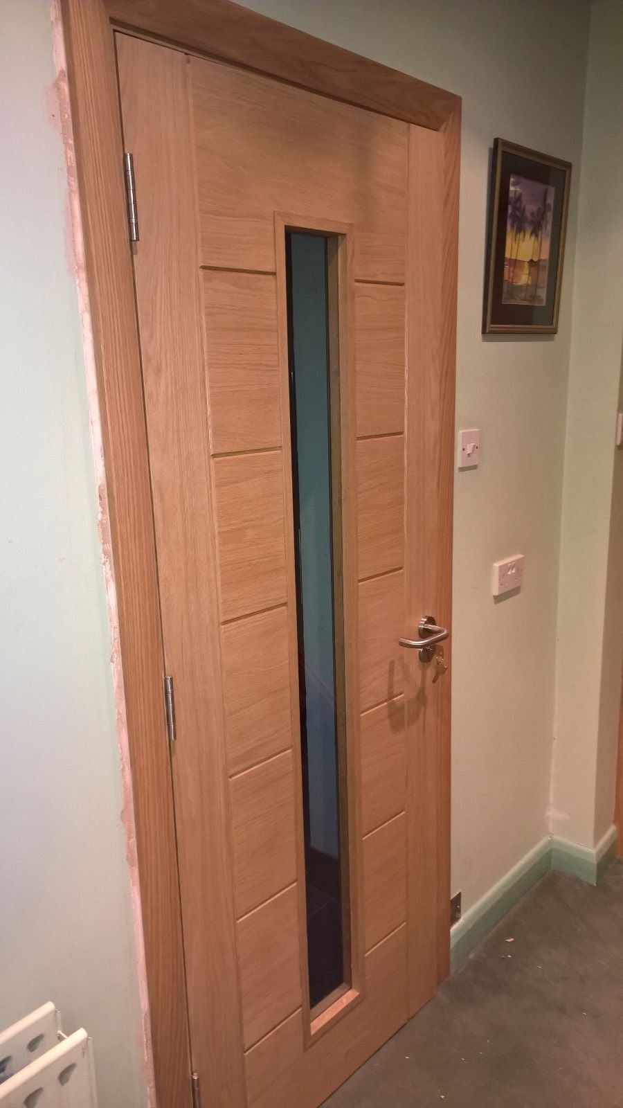 A wooden door with a glass window in a hallway.