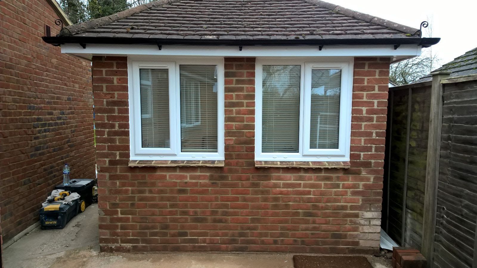 A brick building with white windows and a fence in the background.