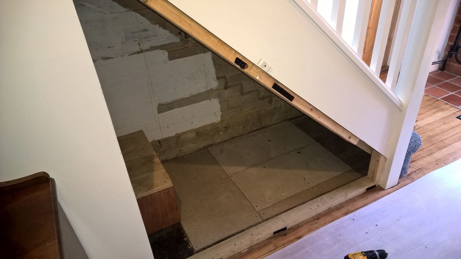 A door is open under a staircase in a room.