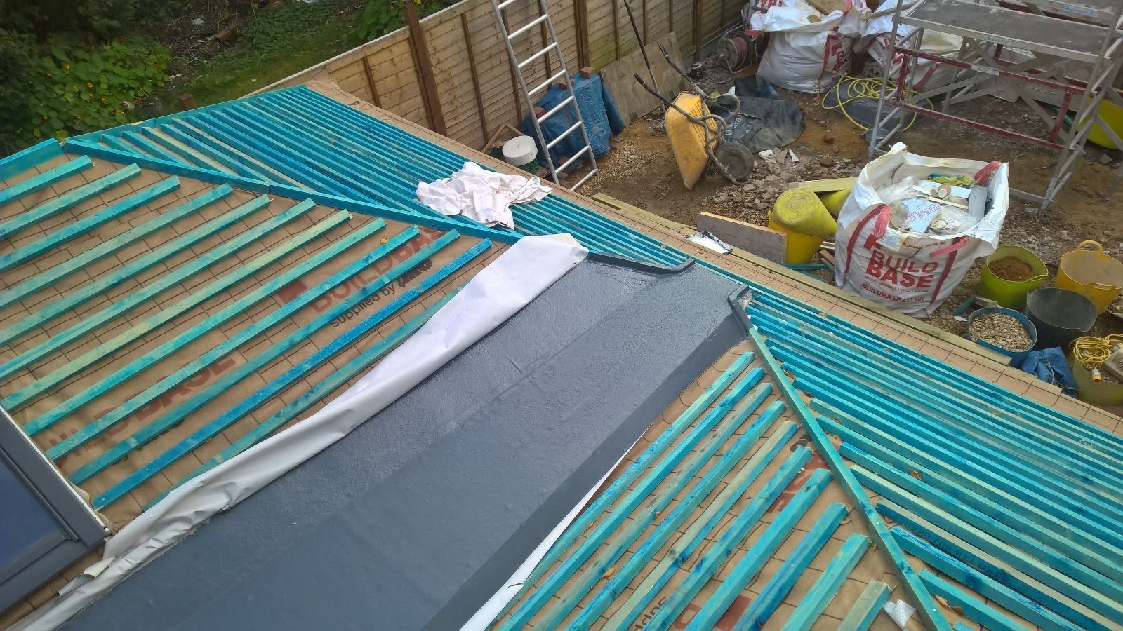 A roof is being built on a house with blue wooden beams.