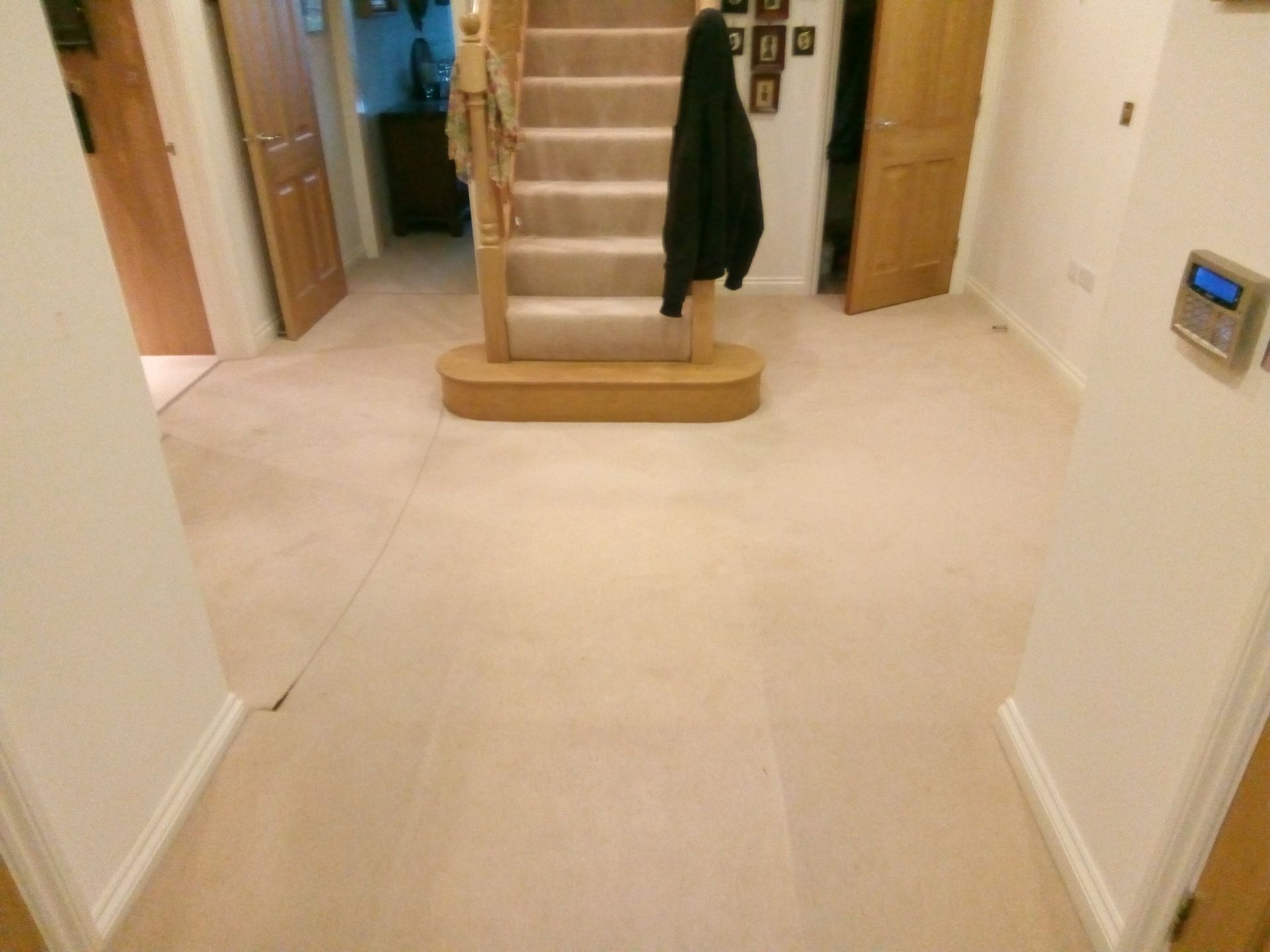 A hallway with stairs and a carpeted floor