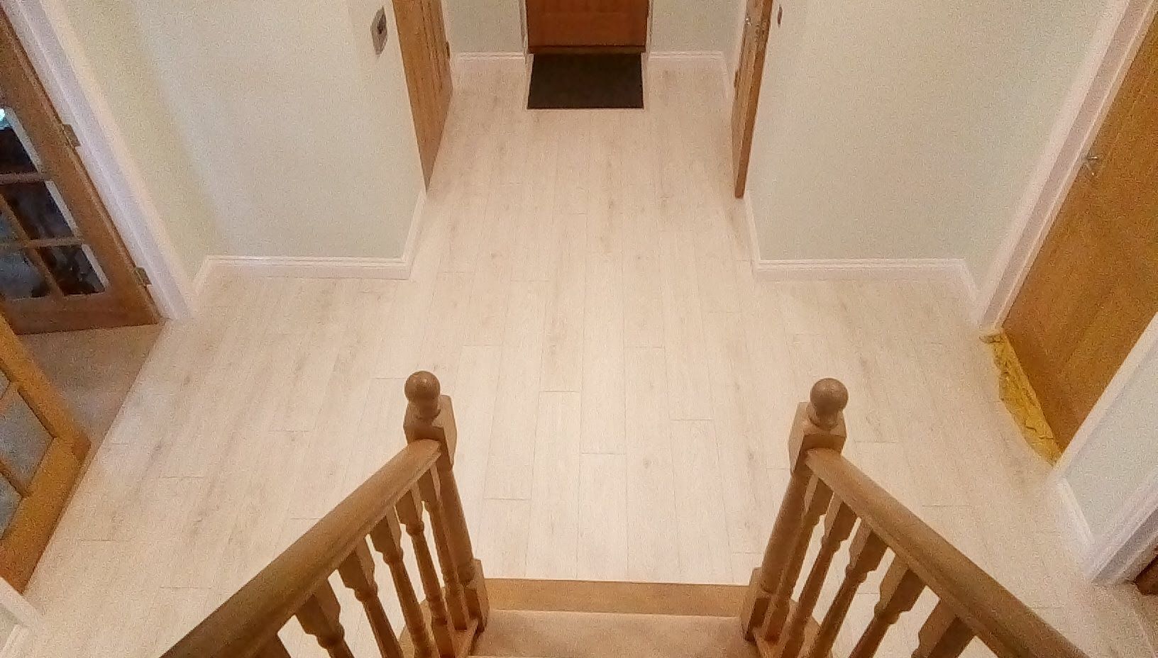 A view of a hallway with stairs and a wooden railing.