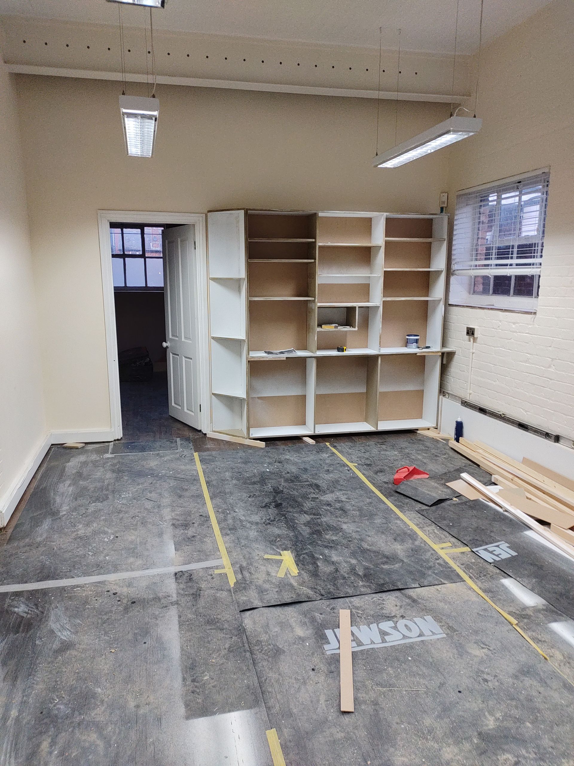 A room with a lot of shelves and a door that is open