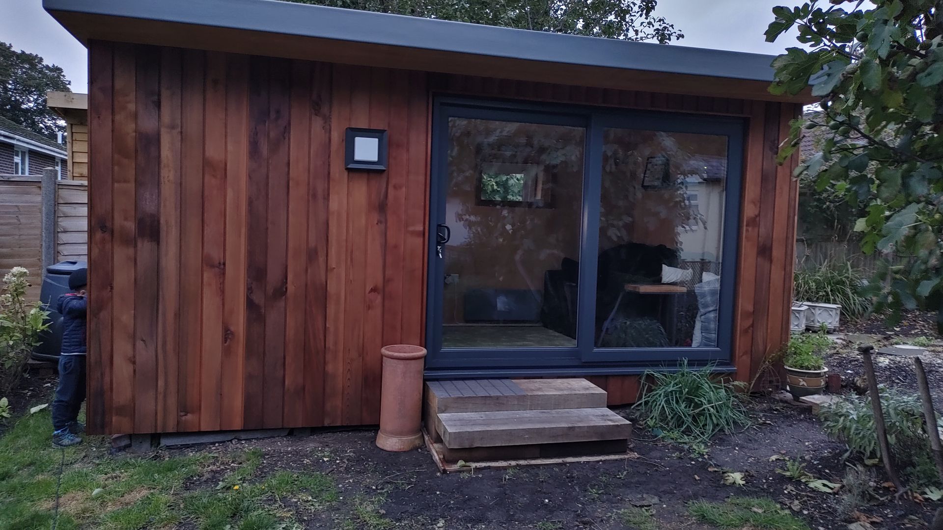 A small wooden house with a sliding glass door in the backyard.
