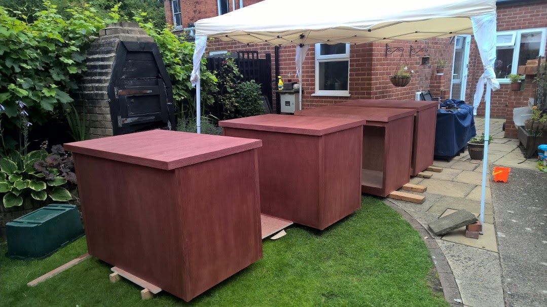A row of wooden boxes sitting on top of a lush green lawn under a white canopy.